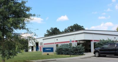 A one-story building surrounded by trees with a sign in the front that reads "nano: experience. customer. service." to convey our Tennessee location