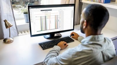 Man working on white screen of computer monitor in home office.