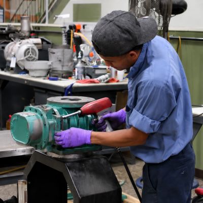 Man servicing mechanical blower pump for repair