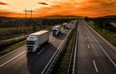 Trucks on highway at sunset