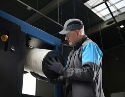 Atlas Copcon asentaja asentamassa suodatinta kompressoriin.