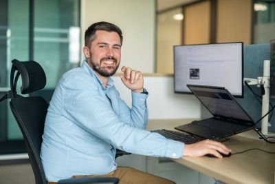 A young man sitting at his desk and smiling.