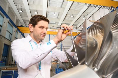 A dynamic employee closely inspecting an impeller of a compressor.