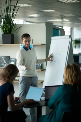 Colleagues in discussion with team while standing in front of white board