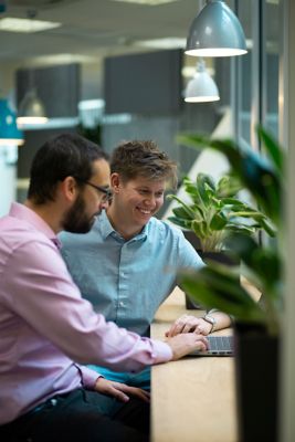 Two colleagues in discussion looking at a laptop screen