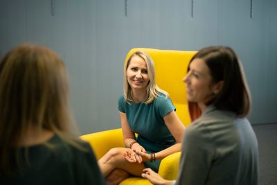 Three women employees in discussion in office lounge