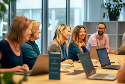 Large team at meeting in conference room with laptops