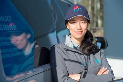 Female service technician standing in front of a service van