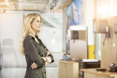 Woman standing inside production plant with hands folded