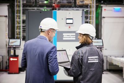 Técnico de servicio en campo, compartiendo datos en un computador portátil.