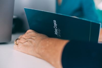 Employee holding a notebook  showcasing Atlas Copco Group branding. Suitable for communication, marketing, or corporate theme.