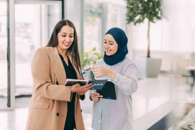 Two women engaged in discussing a project, symbolizing teamwork, collaboration, and modern business in a relaxed office environment.