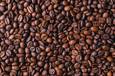 A layer of coffee beans in a variety of brown shades of color