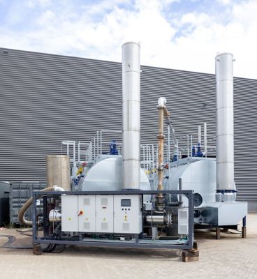Two industrial boilers and a superheater placed outside an building.