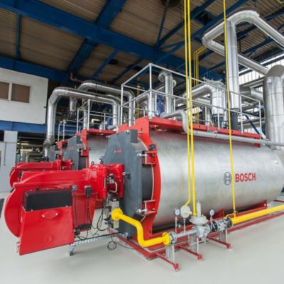 Fixed industrial Bosch warm water boiler installation. The boiler has a metal cylinder housing with a red burner at the front. 
