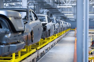 A line of vehicles in a warehouse, waiting for further assembly