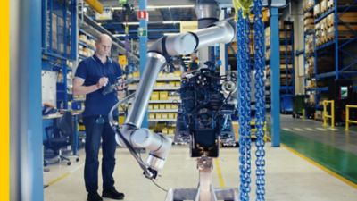 Factory technician operating a collaborative robot (cobot) in a modern manufacturing facility, showcasing human-robot collaboration for enhanced productivity.