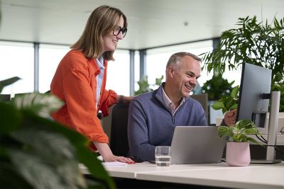 Photo of two people looking at computer screen and discussing something