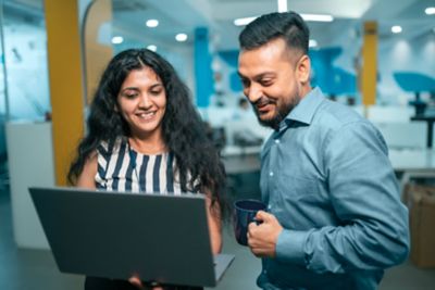 Two colleagues smiling while viewing a laptop