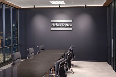 A conference room with an Atlas Copco logo in grey on the wall.