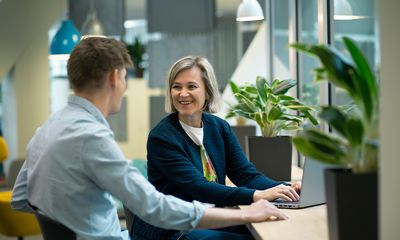 Two colleagues smiling at each other in front of a laptop.