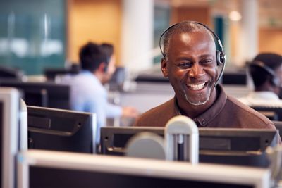 A customer service representative is smiling while wearing a headset