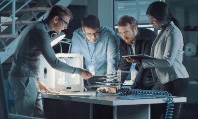 Colleagues inspecting work at the desk.