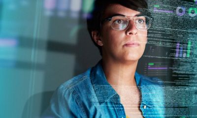 Woman looking at reflection of code on a window.