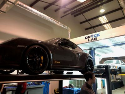 Two classic cars lifted in a "Dryce Nation Lab" area for dry ice cleaning