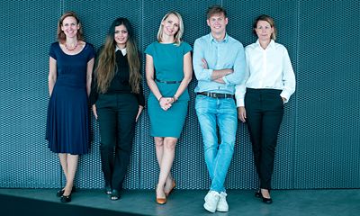 Group of colleagues posing in front of wall.