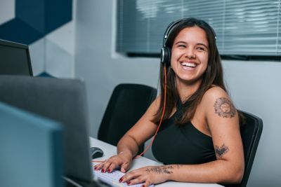 Employee wearing headset at workstation looking around and smiling