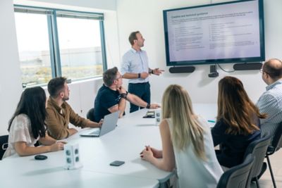 Employeesat a meeting in the conference room looking at the screen