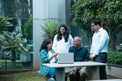 Employees having discussion outdoors around a table on the lawn