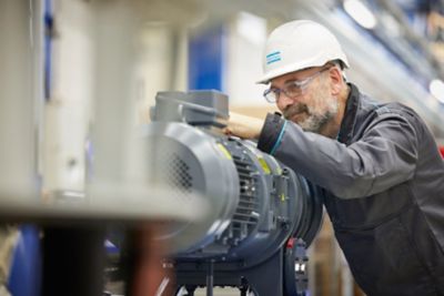 Technician performing hands-on inspection of machinery during a field service visit.