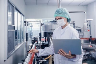 Inspector working at conveyor belt with laptop