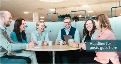 Colleagues sitting around a table in an office environment, smiling and talking.