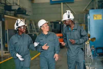 Factory workers in discussion walking down factory floor