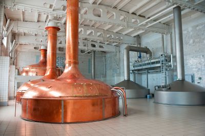 A view of the inside of a brewery with large stainless steel and copper tanks.