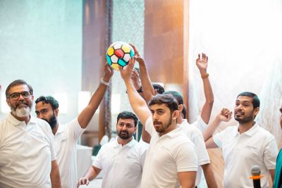 A group of seven male employees in white T-shirts holding a ball.