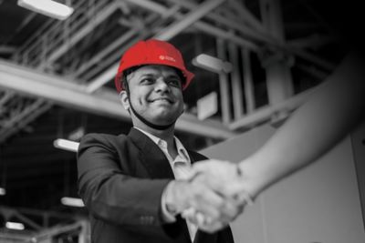 Man in hardhat shaking hand with person out of frame.