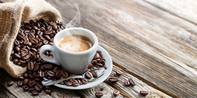 Hot cup of coffee on a plate with coffee beans