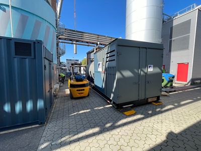 Two boilers placed next to each other in an industrial setting. The sky is bright blue.
