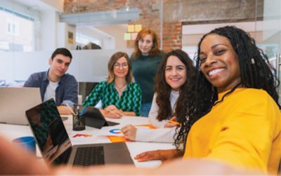 Woman employee taking a selfie with colleagues during a team meeting