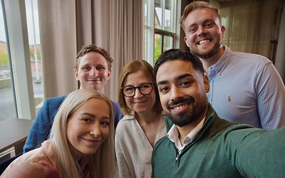 Employee taking a selfie with colleagues in a bright indoor workspace