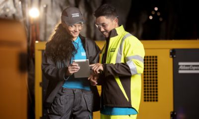 Two colleagues inspecting notes in front of machine.
