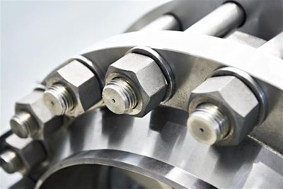 A detailed close-up of a high-strength industrial bolted joint featuring stainless steel bolts and nuts