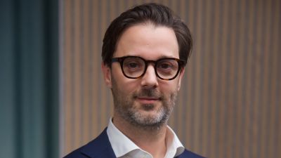 Portrait photo of Jeremy Goossens in white shirt and navy blue blazer. 