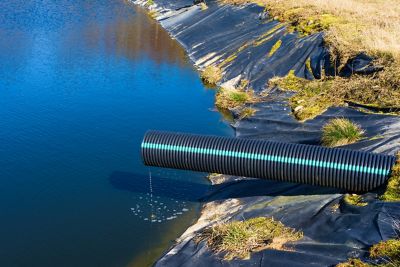 A large black tube sits over a man-made pond, called a leachate