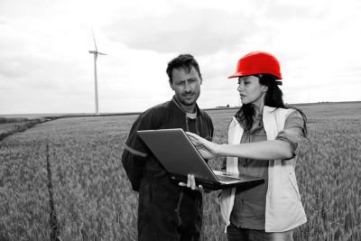A man and a woman looking at a laptop that the woman is holding. She is pointing to something on the screen.