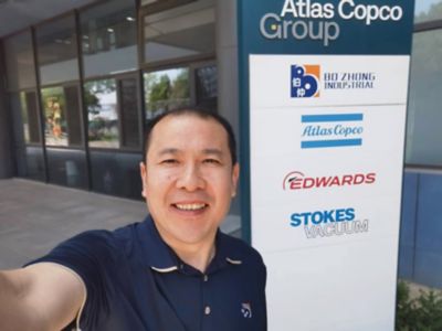 Lawrence Qiu standing by branded sign.